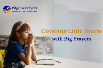 A child praying with a Bible and a Cross in front of her.
