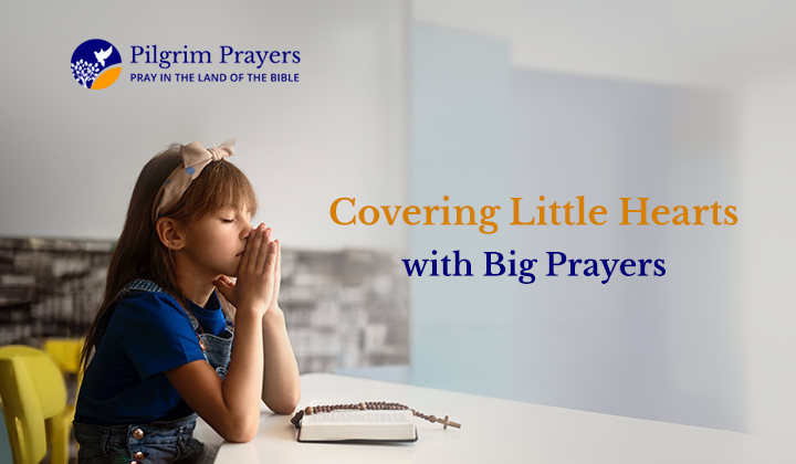 A child praying with a Bible and a Cross in front of her.