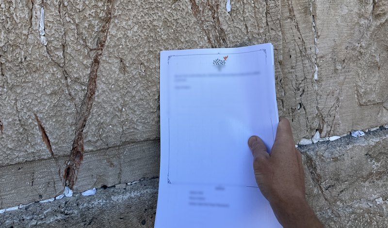 A printed prayer held against the stones of the Western Wall