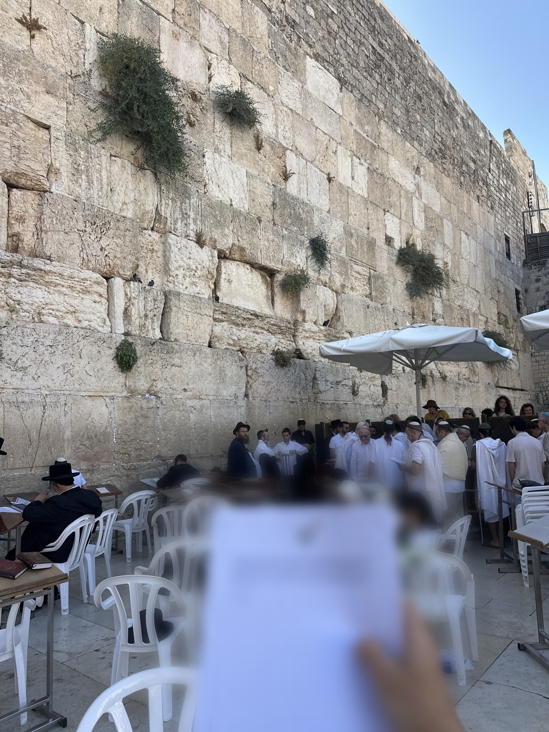 Worshippers at the Western Wall, a prayer held up in the foreground