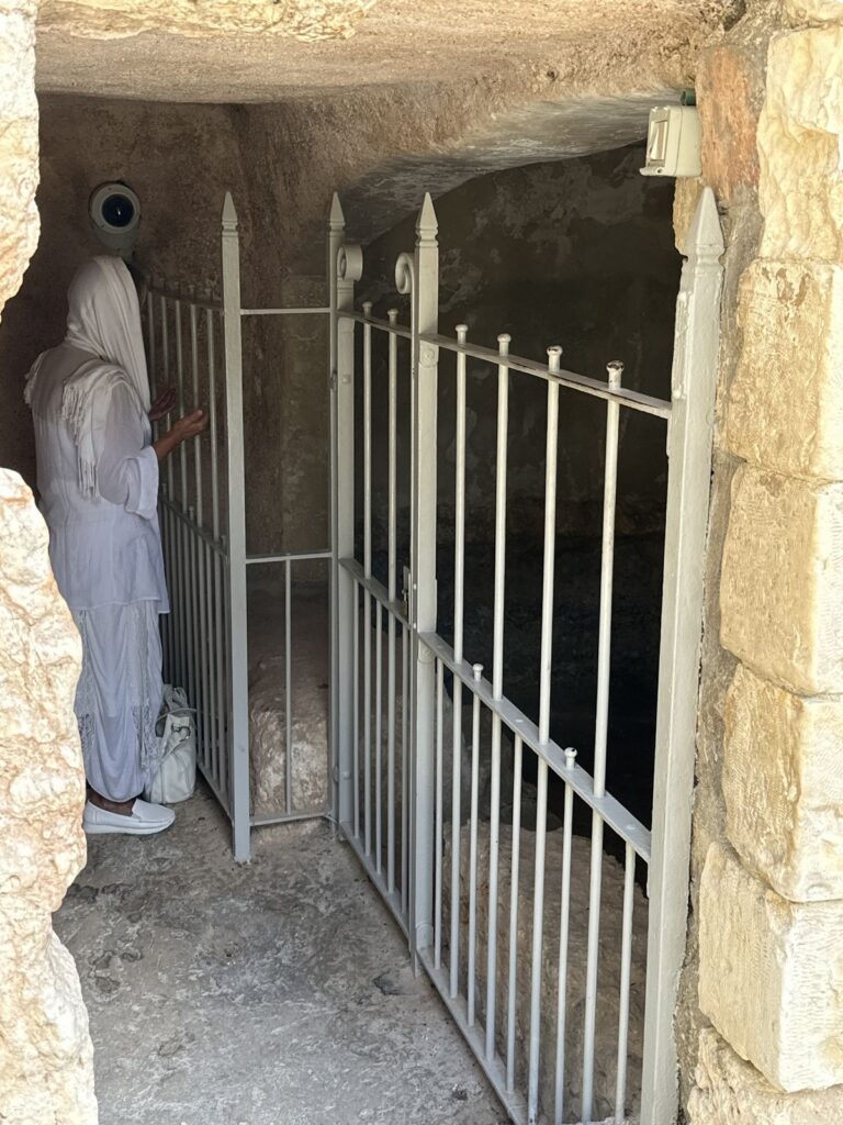 A pilgrim dressed in white standing in prayer inside the Garden Tomb